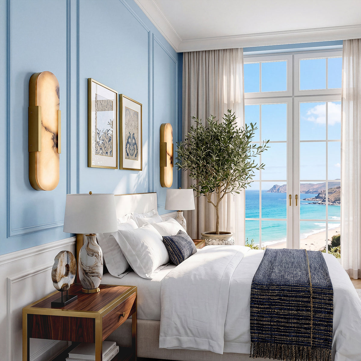 A serene coastal Hamptons bedroom with baby blue paneled walls and French doors opening to an ocean beach view, featuring two elegant oval alabaster wall lights flanking framed artwork.