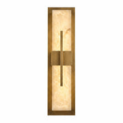 A luxurious linear wall sconce featuring a rectangular Spanish alabaster stone slab framed in brushed brass with a central geometric brass cross bar design, illuminated on a white background.