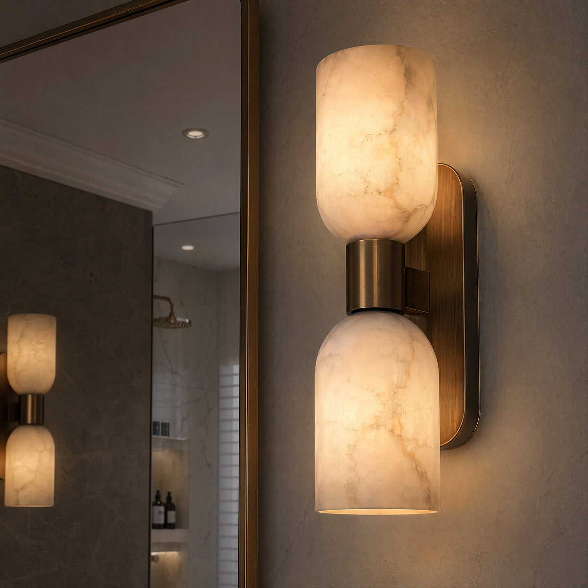 A sophisticated bathroom vanity detail showing a vertical brass and translucent alabaster wall sconce glowing against a concrete plaster wall next to a large mirror.