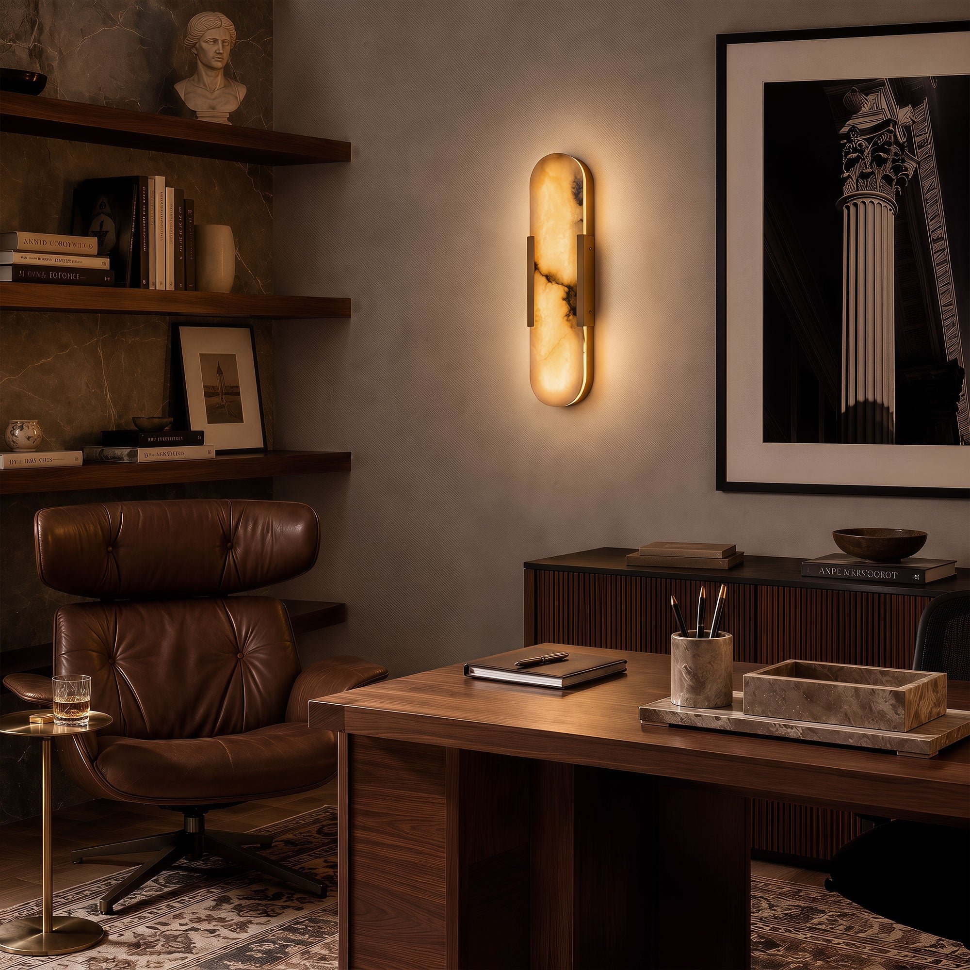 A moody mid-century modern home office with a rich leather lounge chair, a walnut desk, and a glowing vertical capsule alabaster stone wall fixture casting a warm ambient light.