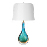 A premium Murano style blown glass table lamp with a teardrop shape showing subtle blue and gold ribbon swirls inside heavy clear glass paired with a white shade on white background.