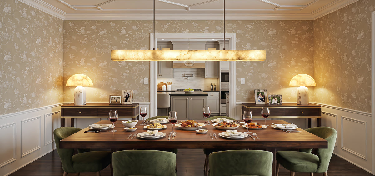 A serene, sunlit quiet luxury dining room showcasing an elegant alabaster linear chandelier suspended over a wooden table and matching alabaster accent lamps under daylight.