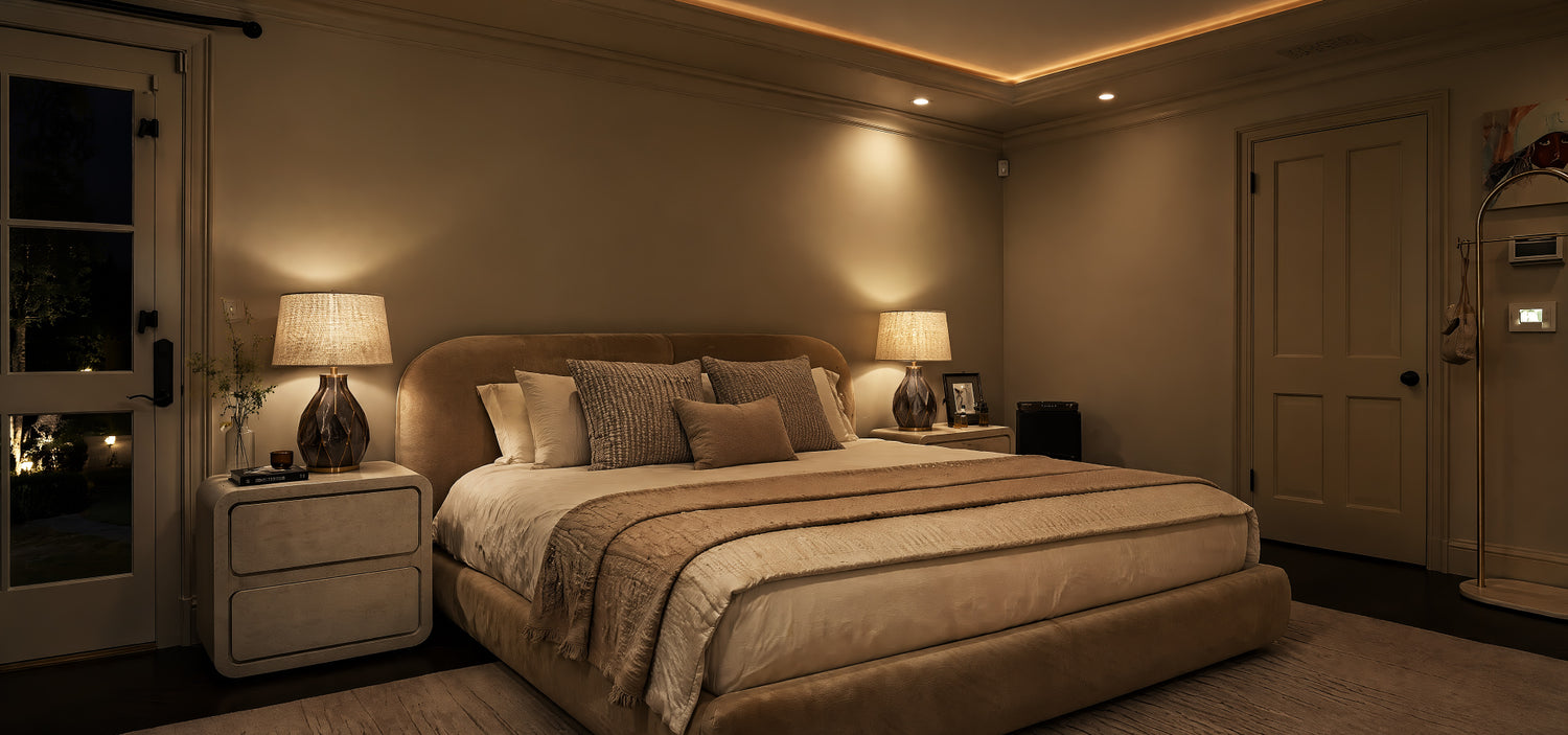 A moody nighttime luxury bedroom lit by a pair of marble bedside lamps with textured fabric shades casting a cozy, warm ambient glow over a velvet bed.
