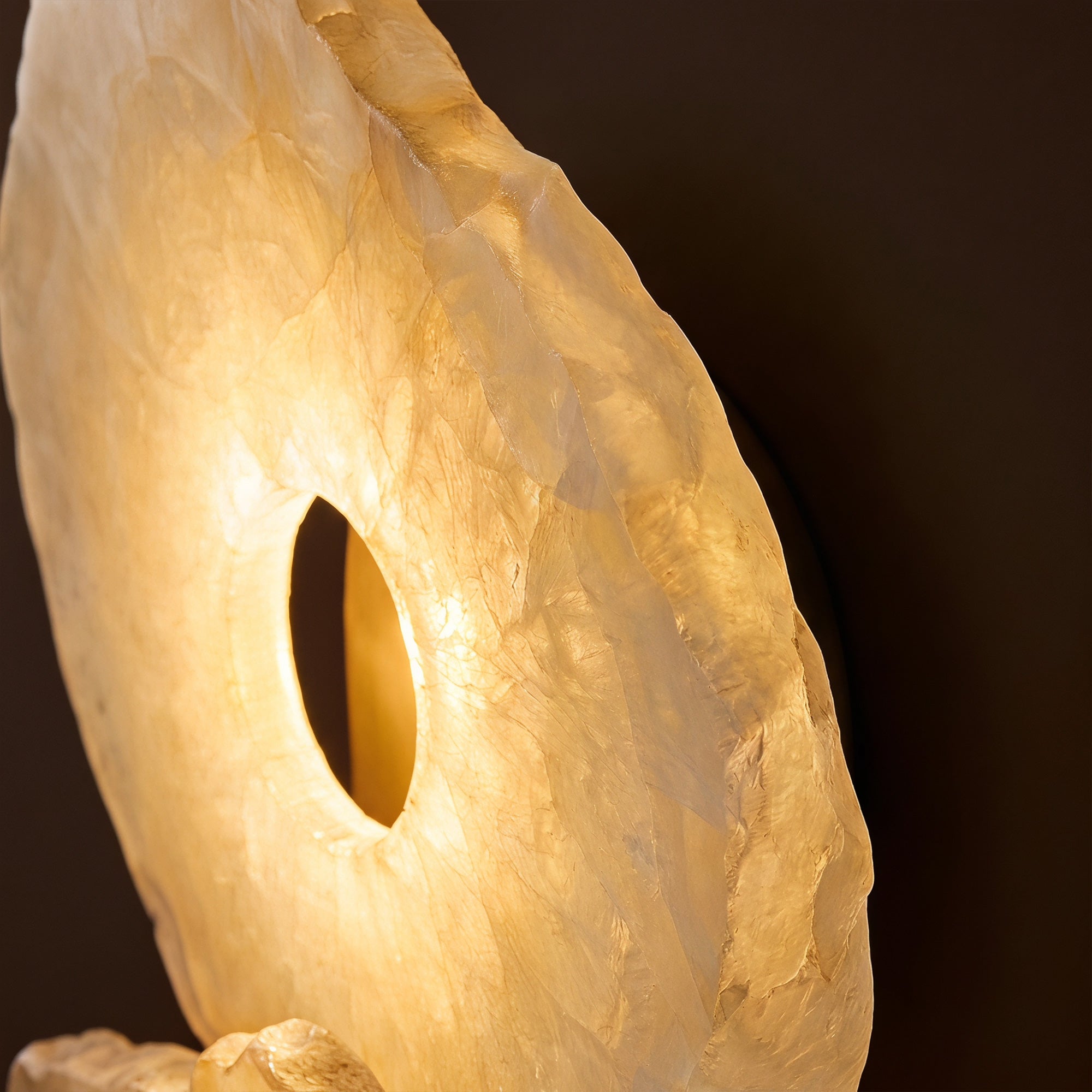 Side view detail of a high-end wall light showcasing the hand-chipped organic raw edge of Spanish alabaster stone.