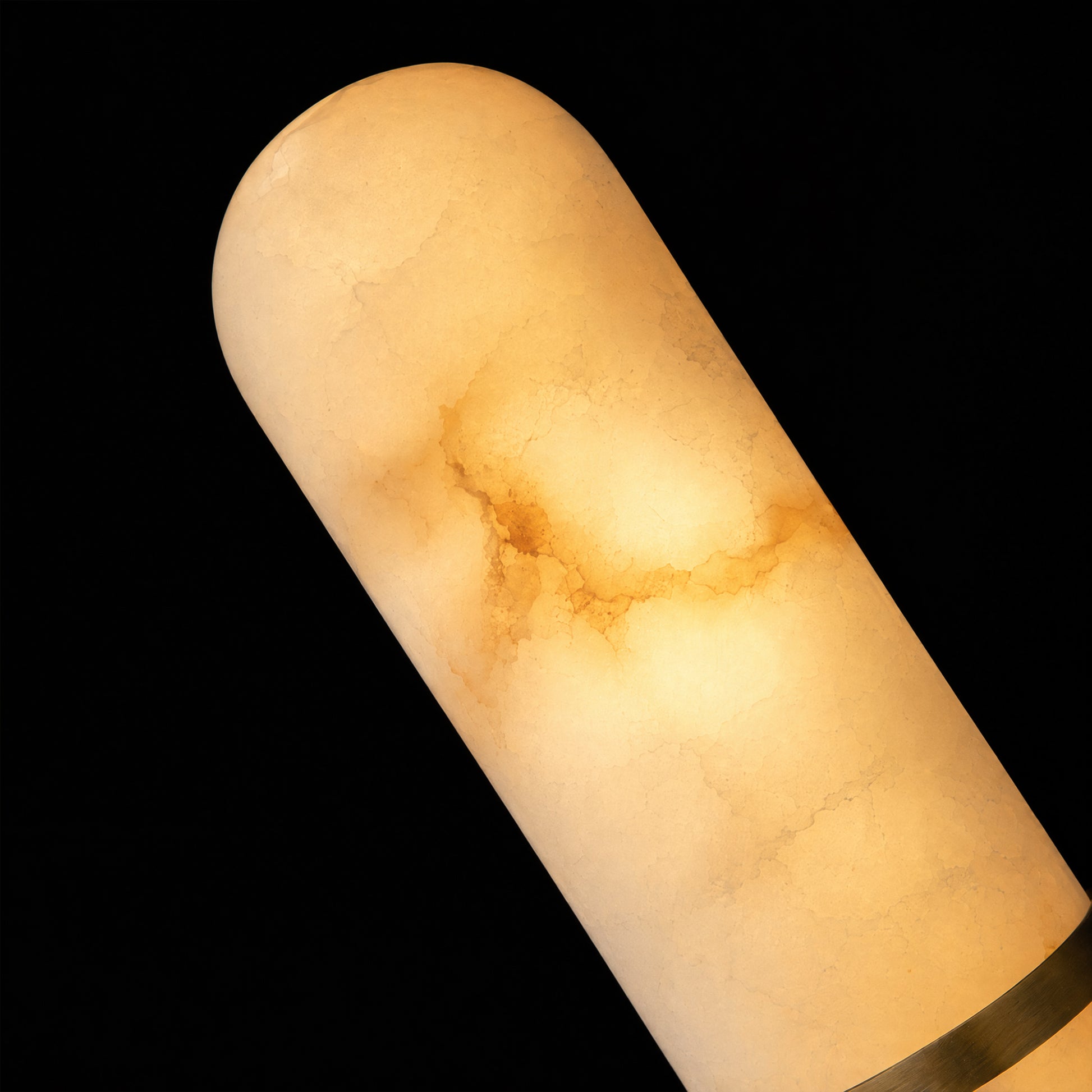 Macro close-up detail shot showcasing the rich, natural dark veining and cloudy texture of a capsule-shaped Spanish alabaster wall sconce when illuminated.