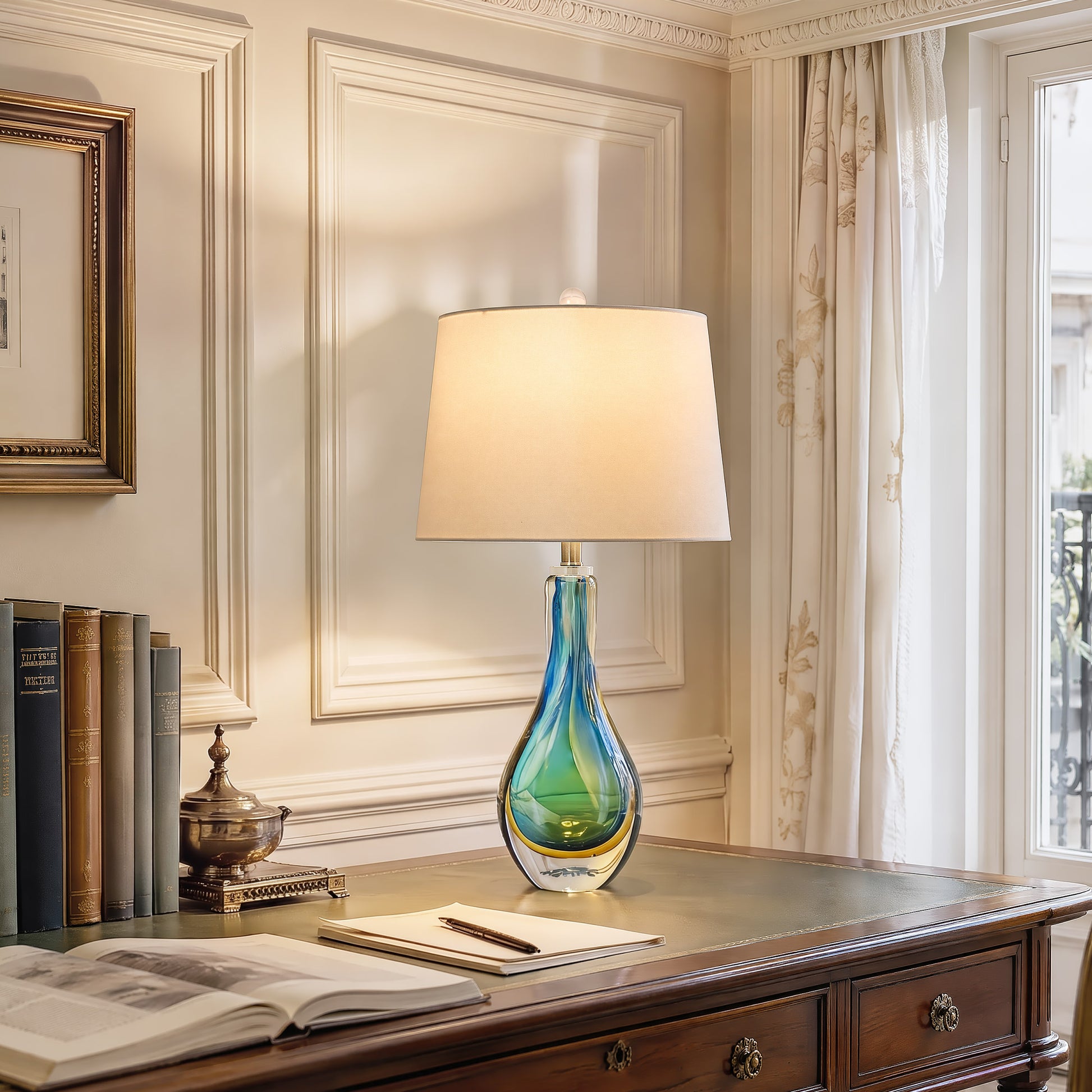 A classic executive home office with wooden wainscoting panels featuring a glowing coastal blue glass table lamp casting warm light on a vintage leather top writing desk.
