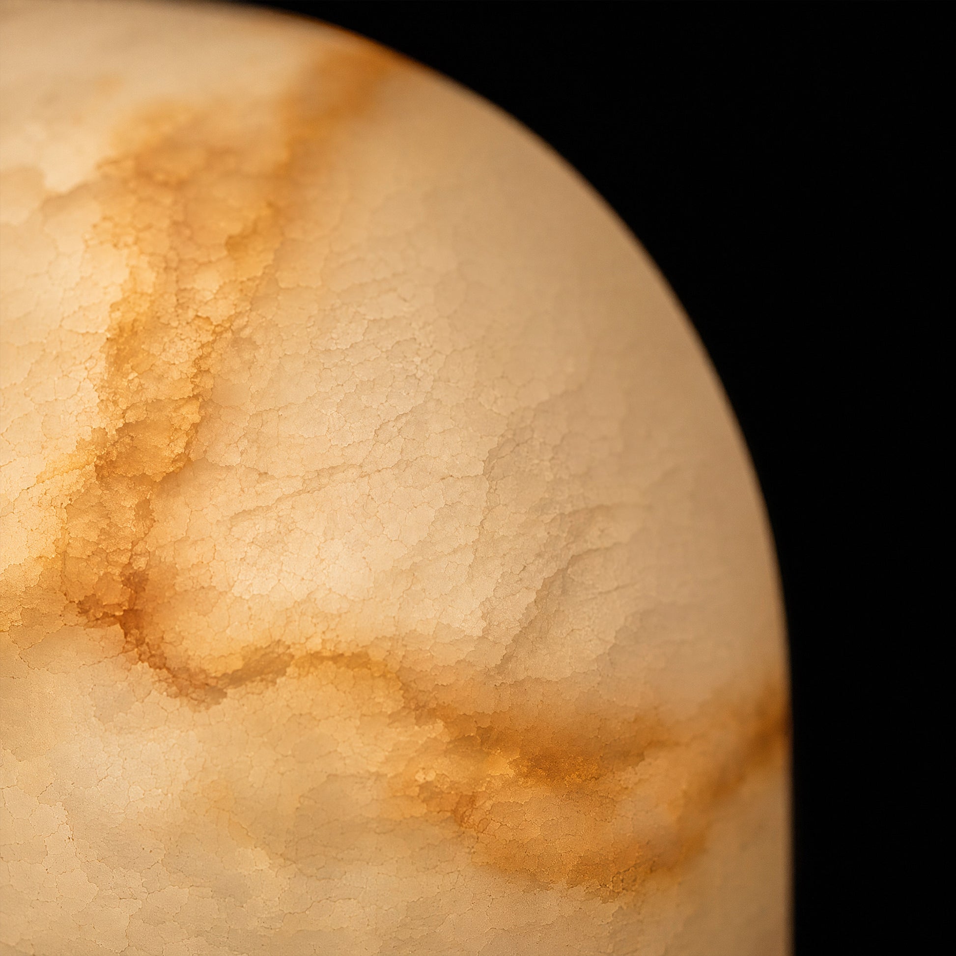 An extreme close-up view highlighting the unique crystalline surface structure and warm translucent glow of a polished natural alabaster stone wall fixture.