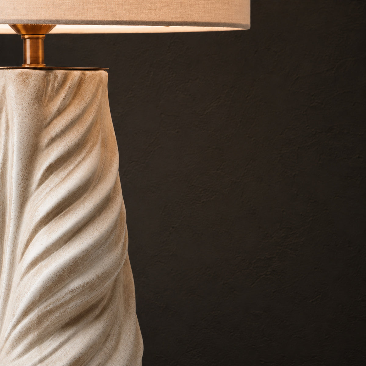 Macro shot of the upper section of a glowing fluted ceramic lamp featuring premium gold brass hardware below the shade