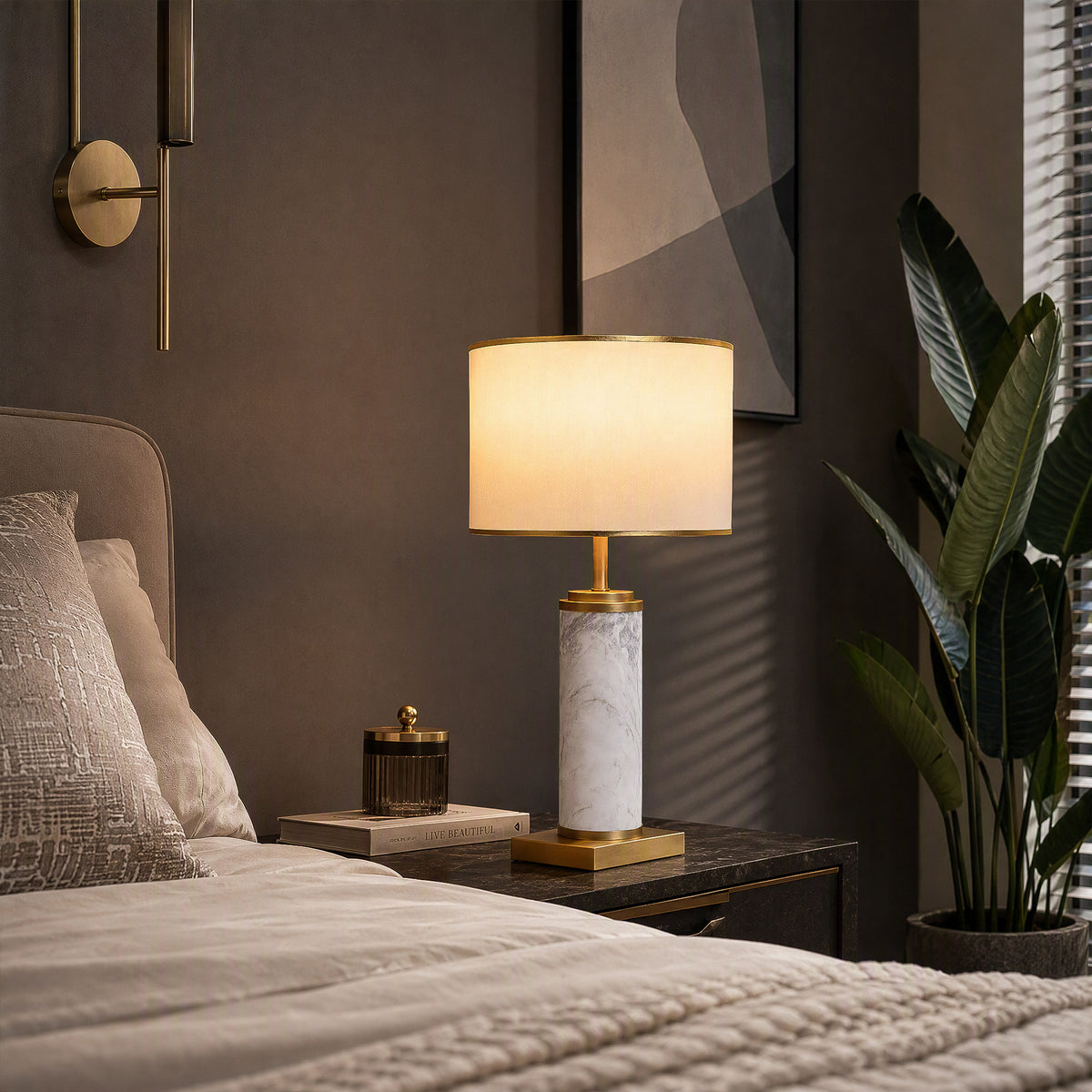 Illuminated white marble table lamp on dark nightstand beside modern upholstered bed