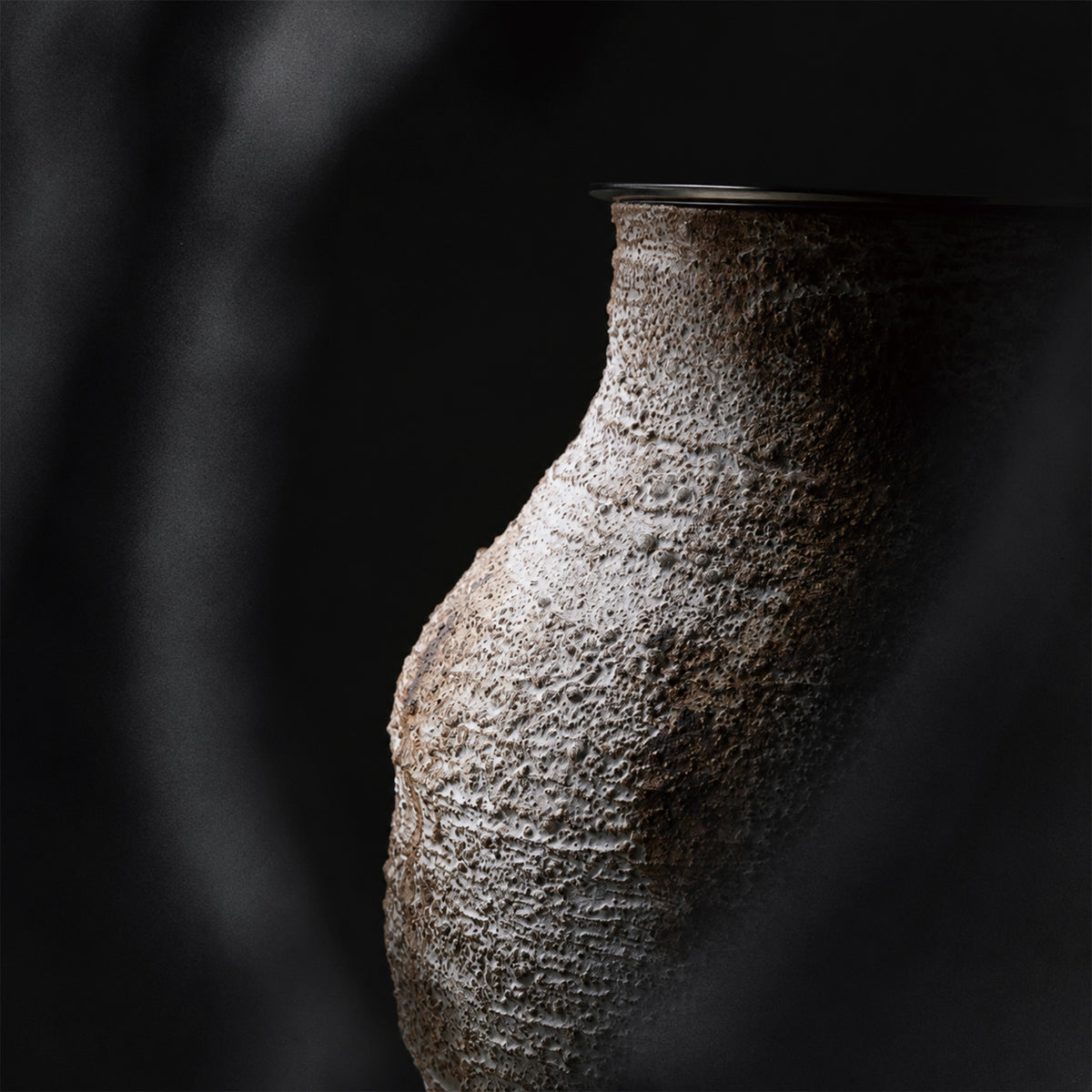Close up detailed view of the rough textured weathered clay ceramic table lamp base showing artisan craftsmanship.