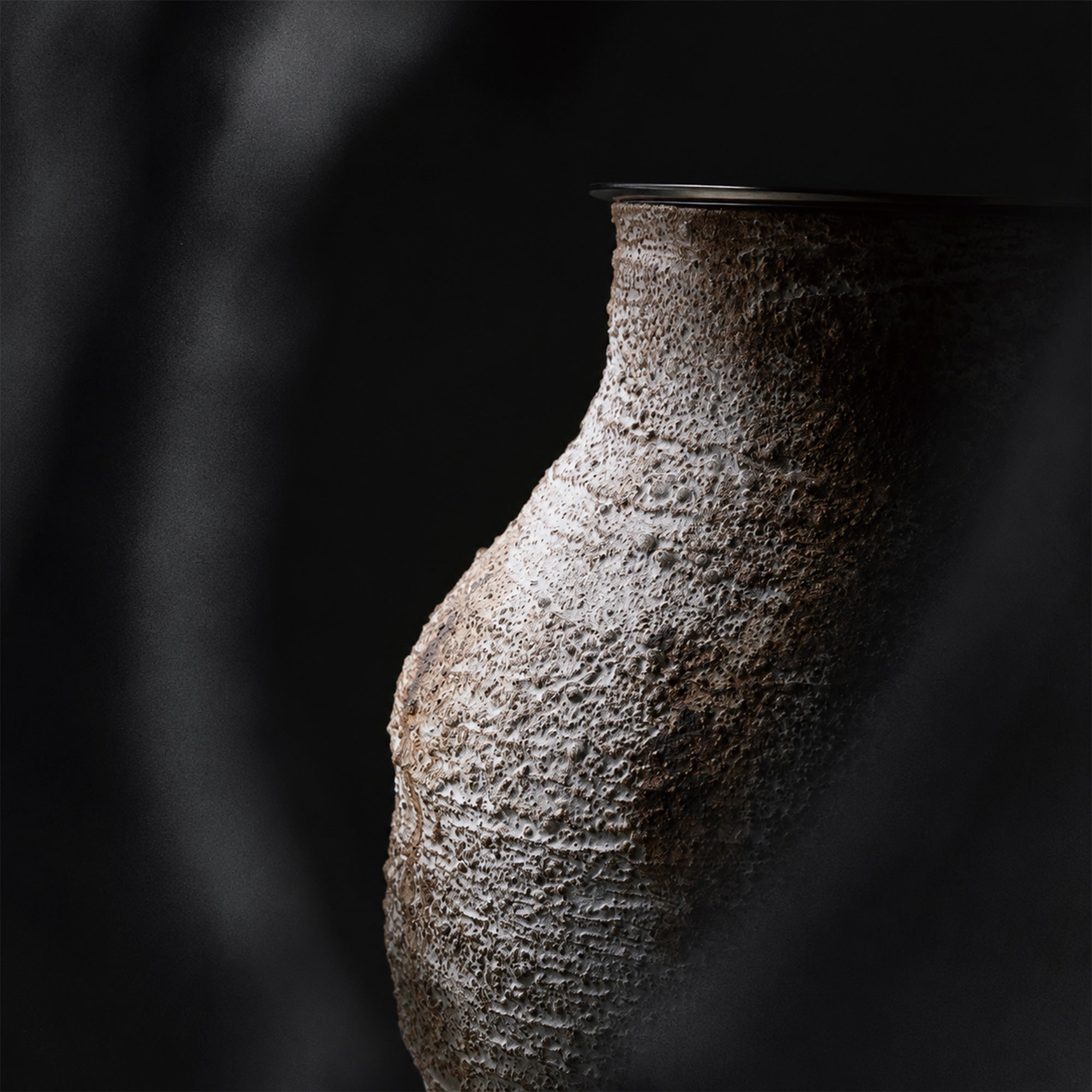 Close up detailed view of the rough textured weathered clay ceramic table lamp base showing artisan craftsmanship.
