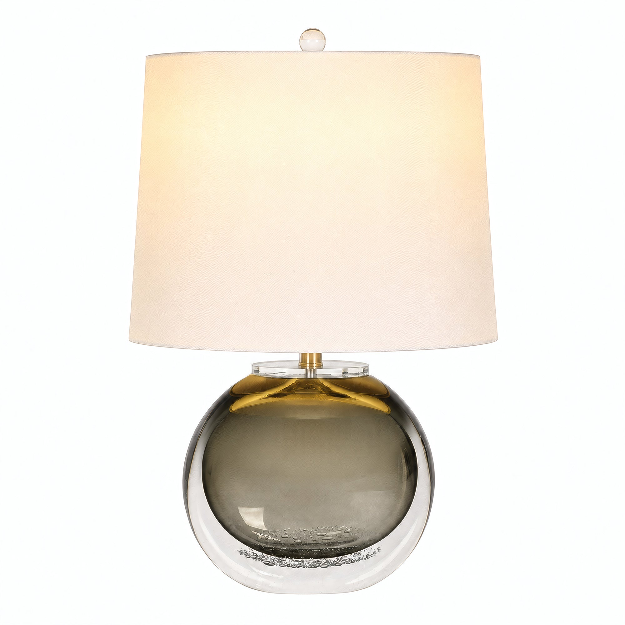 Smoke gray art glass table lamp illuminated with warm glow and white drum shade on white background