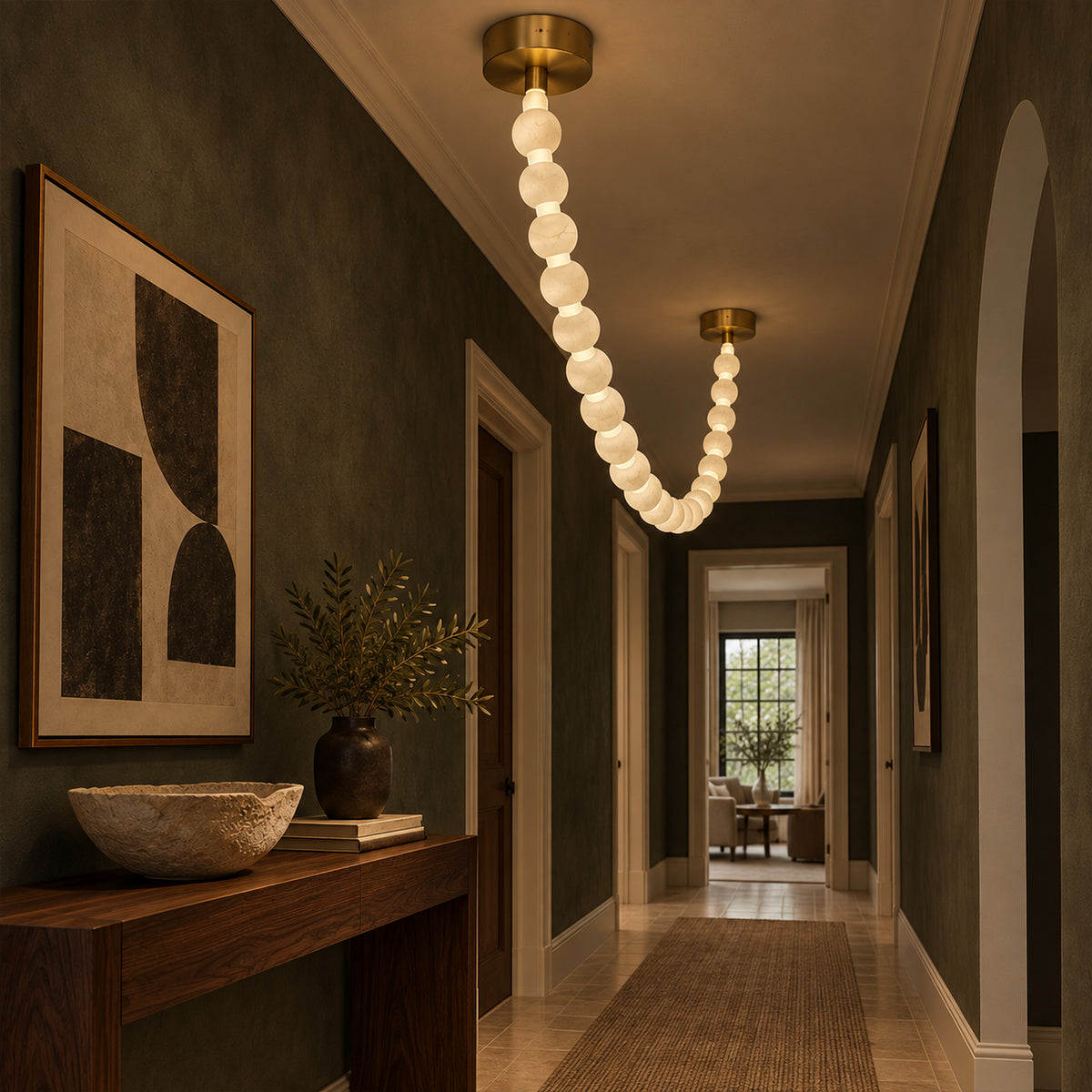 Glowing Spanish alabaster sphere necklace pendant light installed along a luxurious dark green corridor ceiling