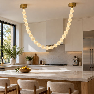 Contemporary alabaster sphere beaded pendant light suspended above a bright kitchen island in a minimalist modern kitchen
