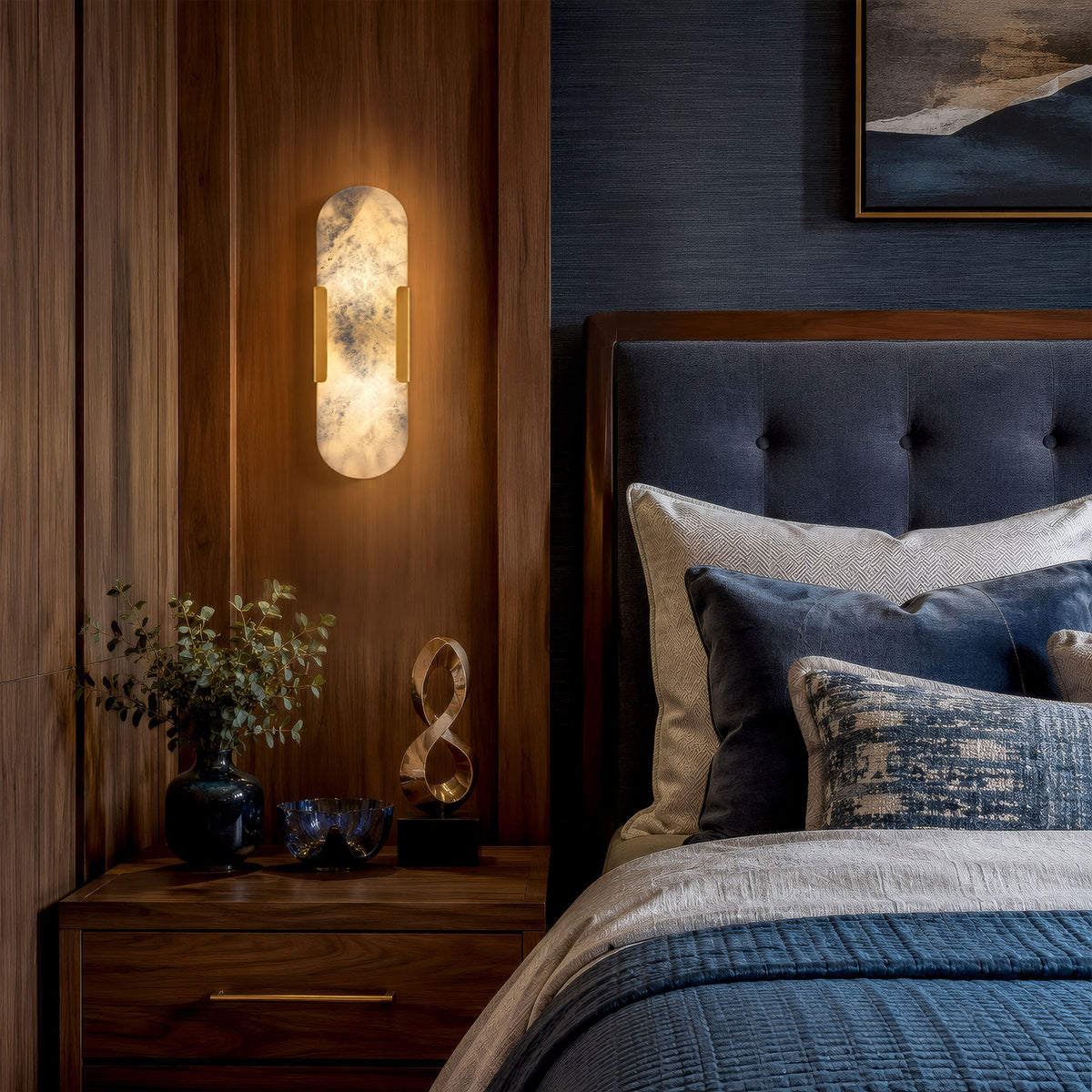 Glowing oval capsule Spanish alabaster wall sconce installed on dark walnut wood paneling beside a bed