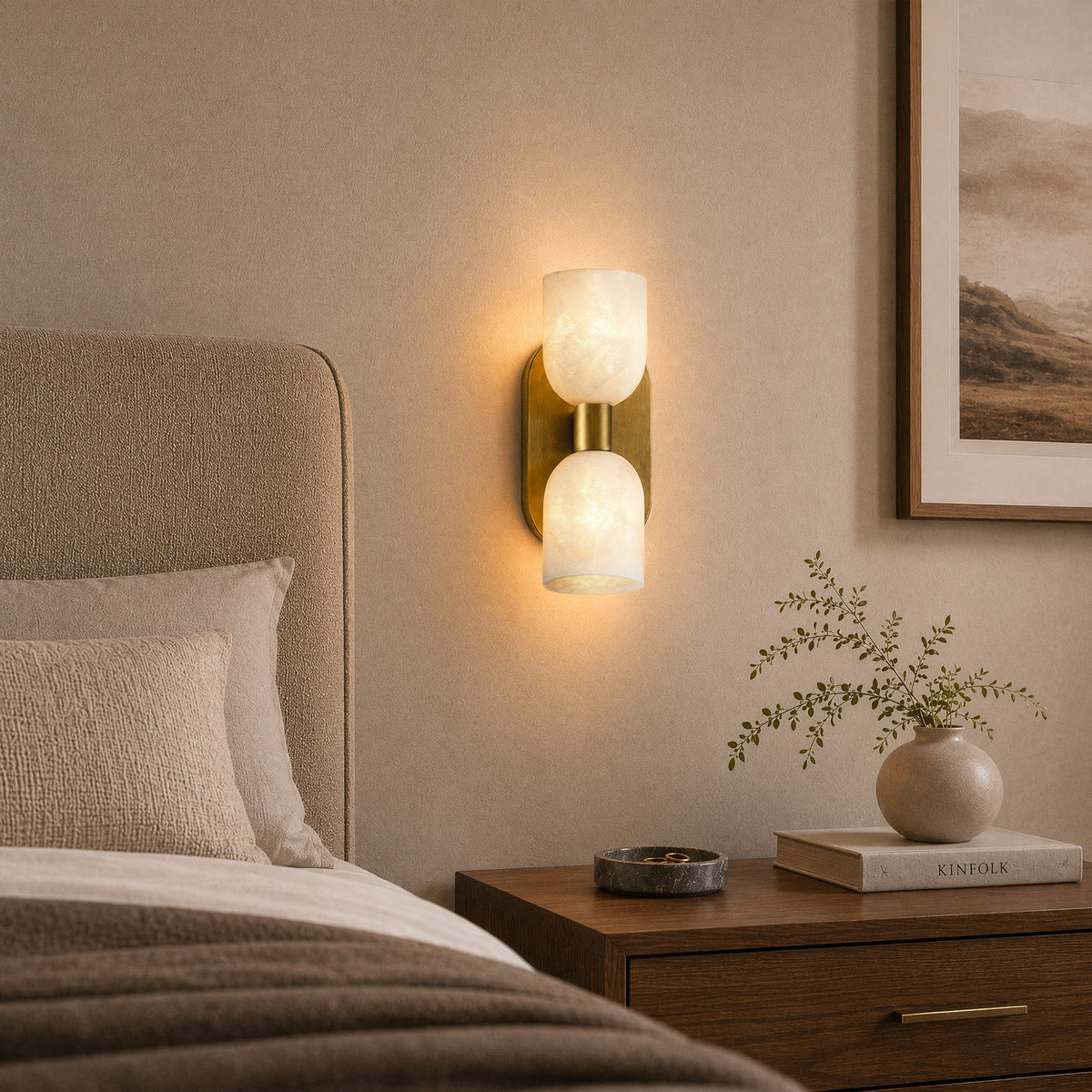 Glowing double capsule Spanish alabaster wall sconce mounted beside upholstered headboard in cozy bedroom