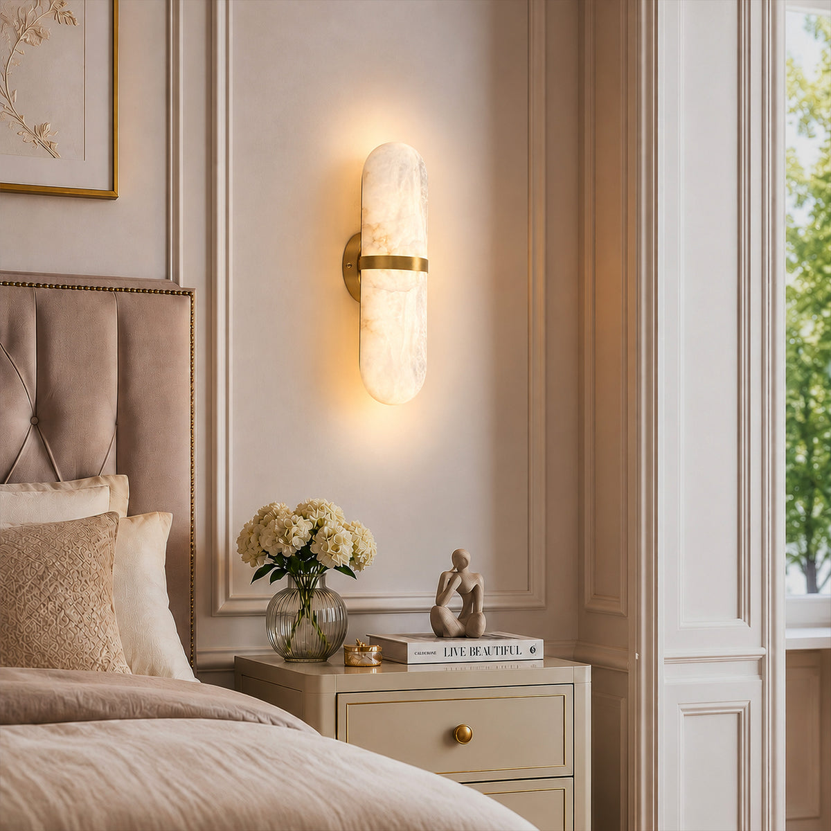 Warmly lit Spanish alabaster capsule sconce mounted as a bedside light above a nightstand in an elegant bedroom