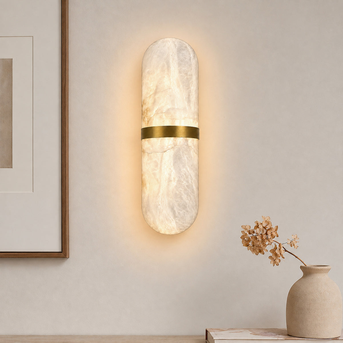 Glowing Spanish natural alabaster capsule wall light mounted on a beige entryway wall above a console table with vase decoration