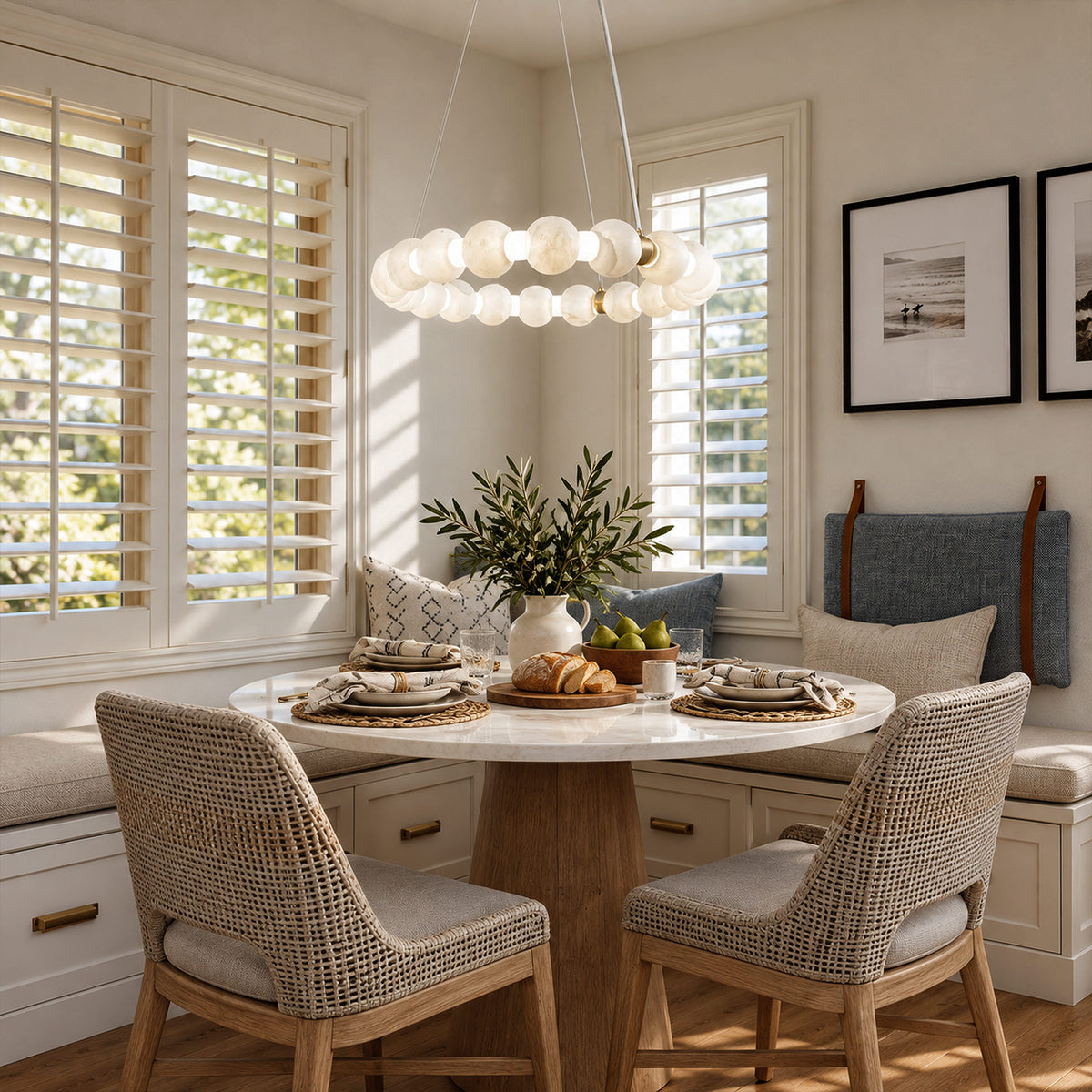 Spanish alabaster orb ring chandelier casting warm light over a round marble breakfast table with woven chairs