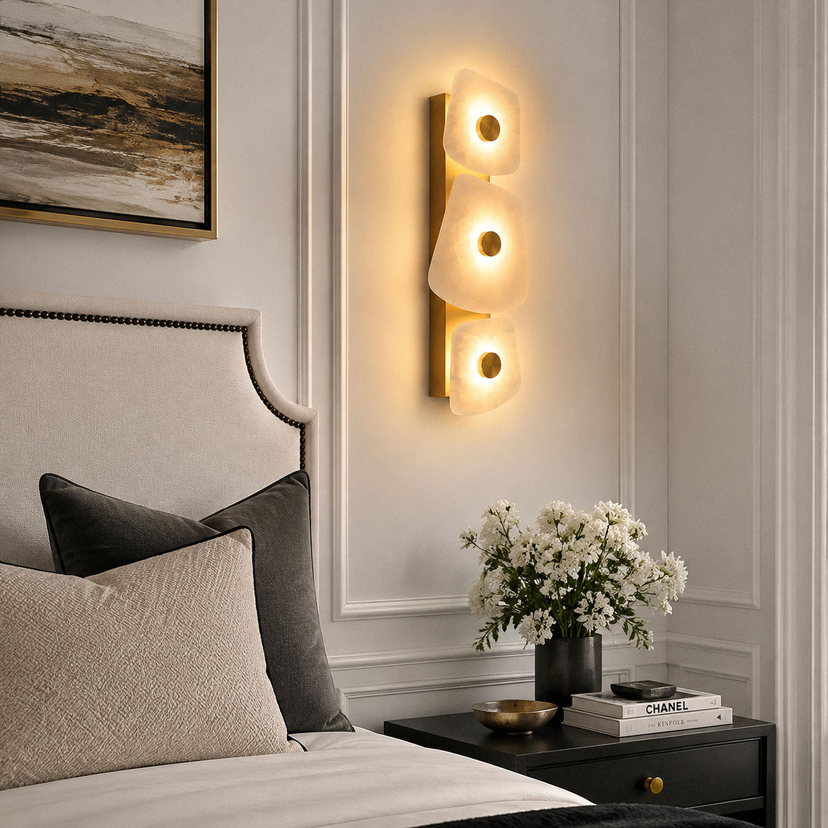 Spanish alabaster stone wall sconce mounted above dark nightstand with white flowers beside bed