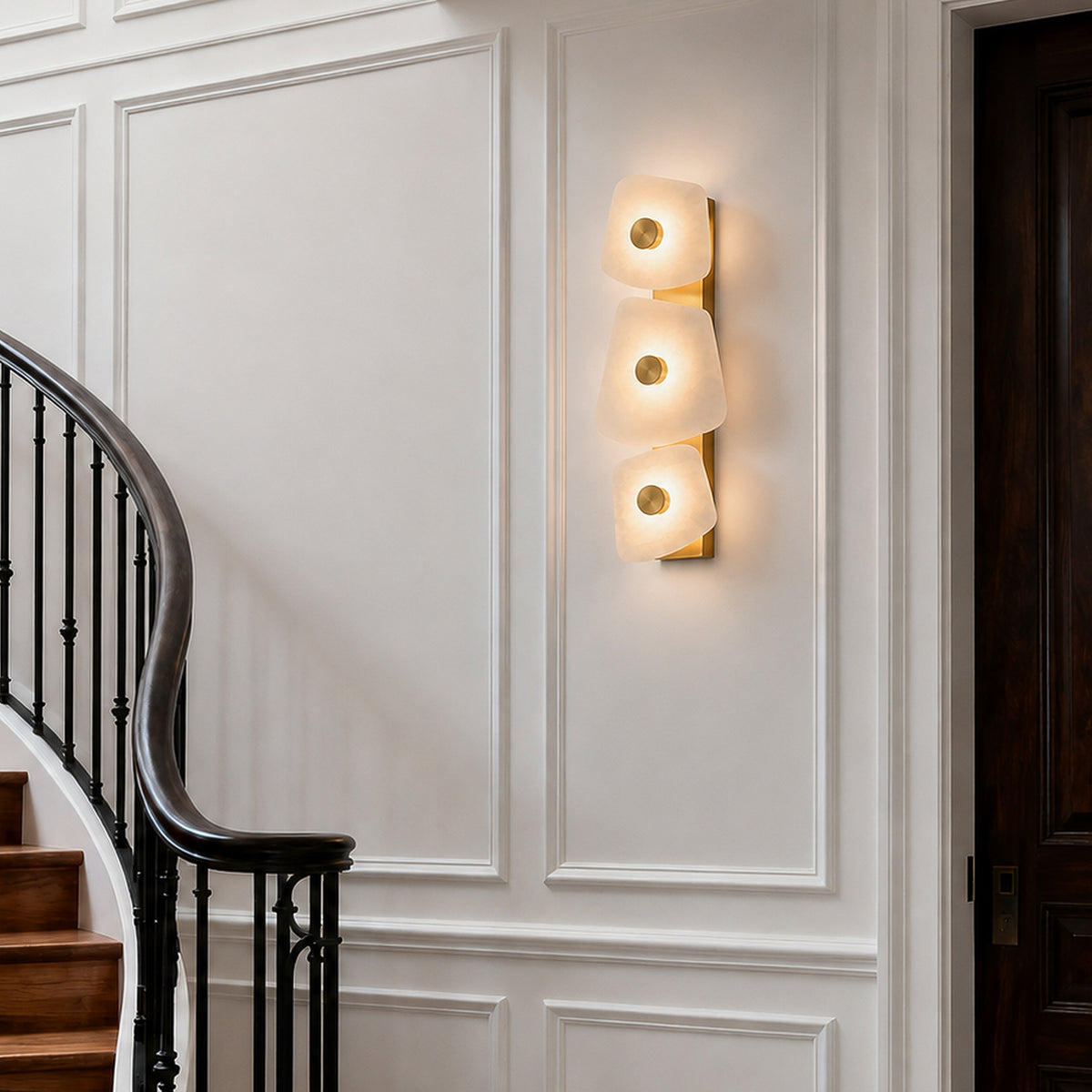 Tiered Spanish alabaster wall sconce mounted on white molded wall panel near dark entry door