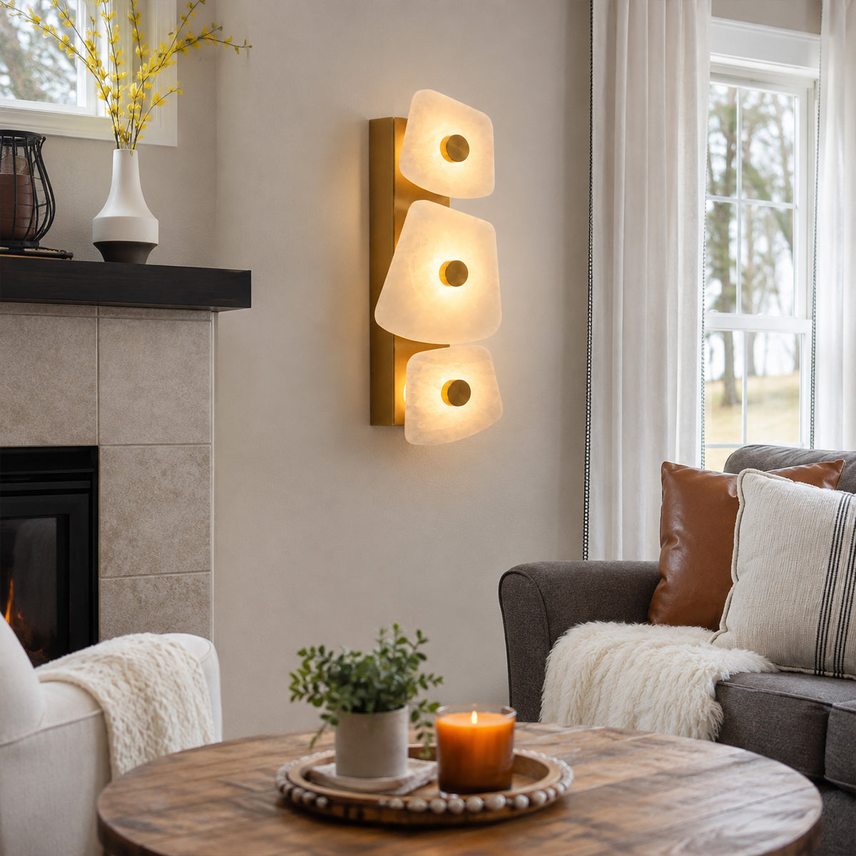 Organic Spanish alabaster wall sconce glowing beside fireplace and sofa in cozy living room