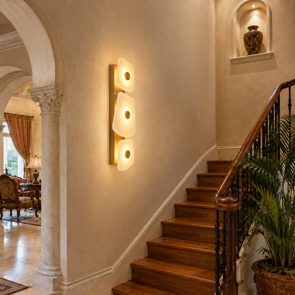 Tall organic Spanish alabaster wall sconce glowing on wall along traditional wooden staircase