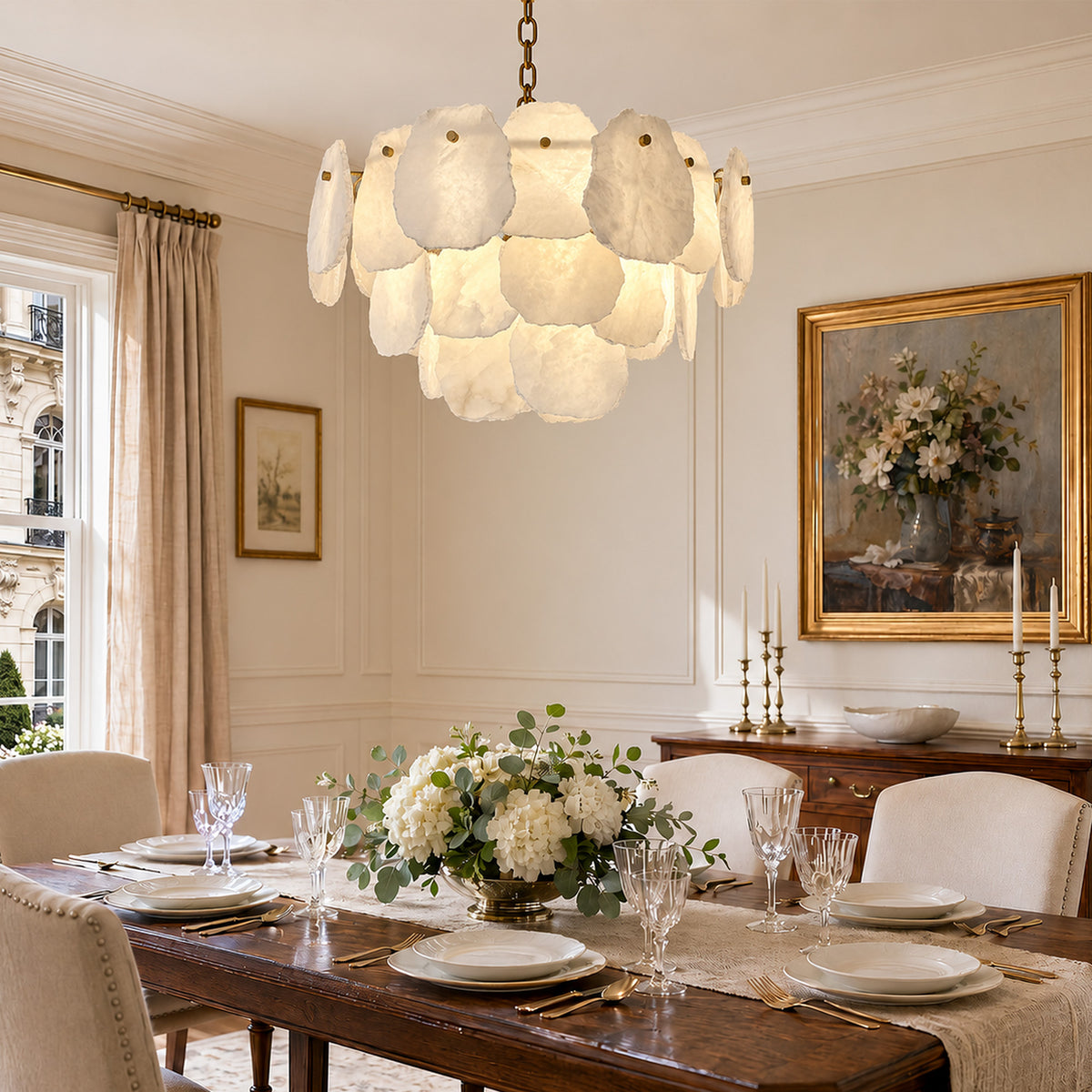Warmly lit Spanish alabaster tier chandelier suspended over an elegant wood dining table set for a formal dinner