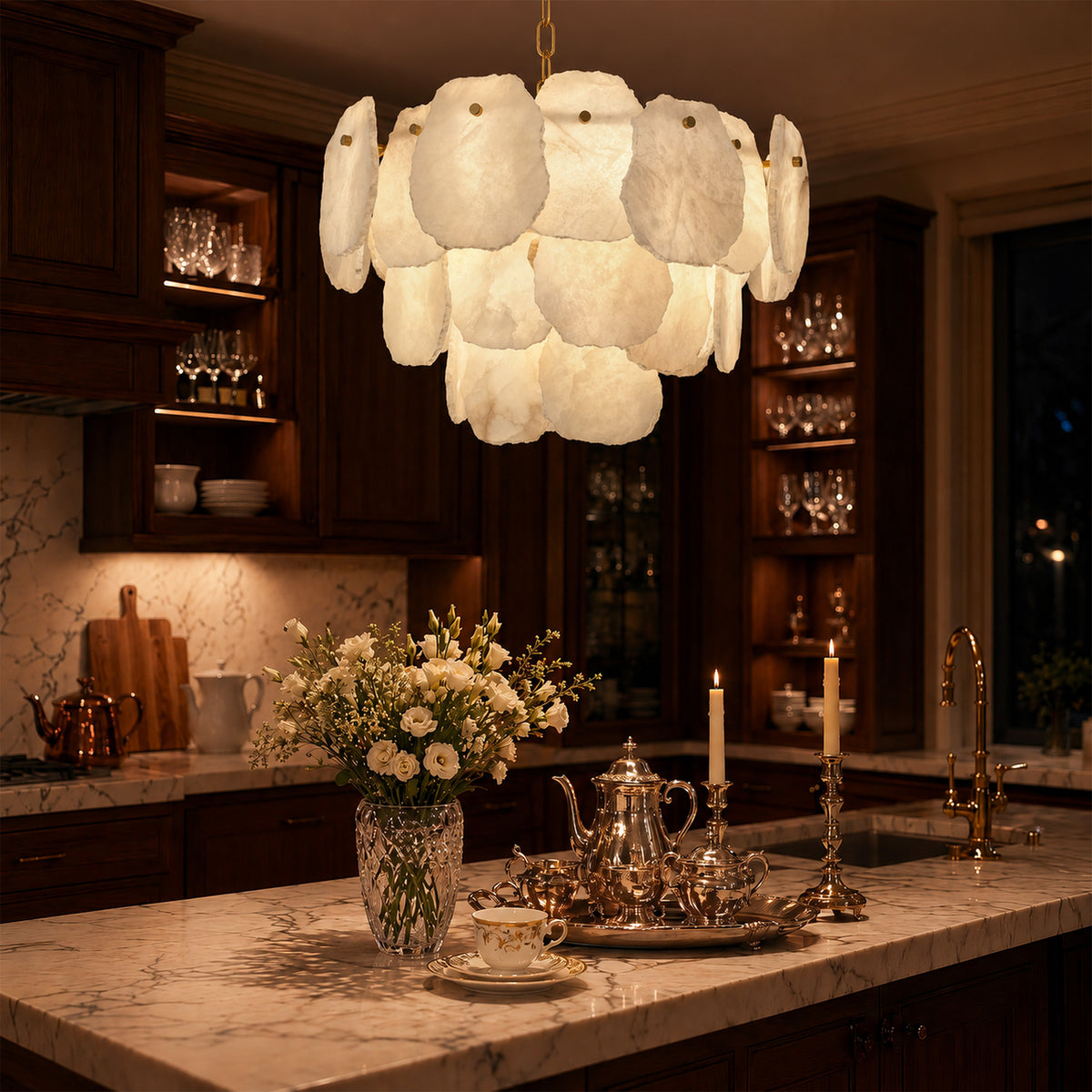 Warmly glowing Spanish alabaster slice chandelier hanging over a marble countertop kitchen island surrounded by dark mahogany cabinets