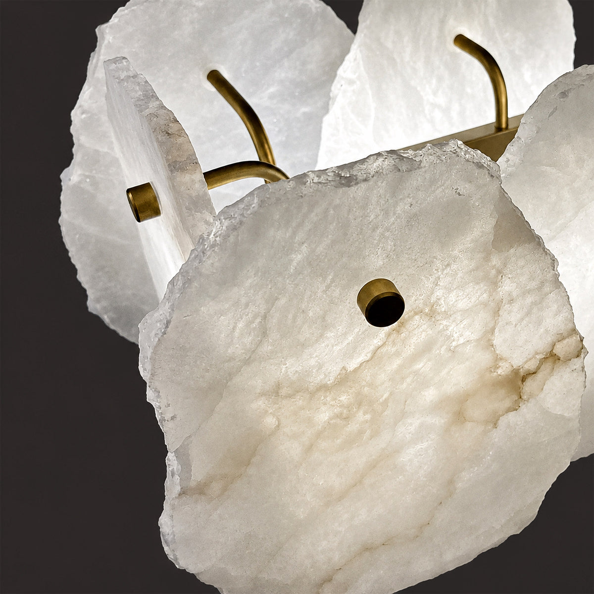 Close up of raw chiselled edge Spanish alabaster slab showing illuminated natural vein pattern and brass stud fixture