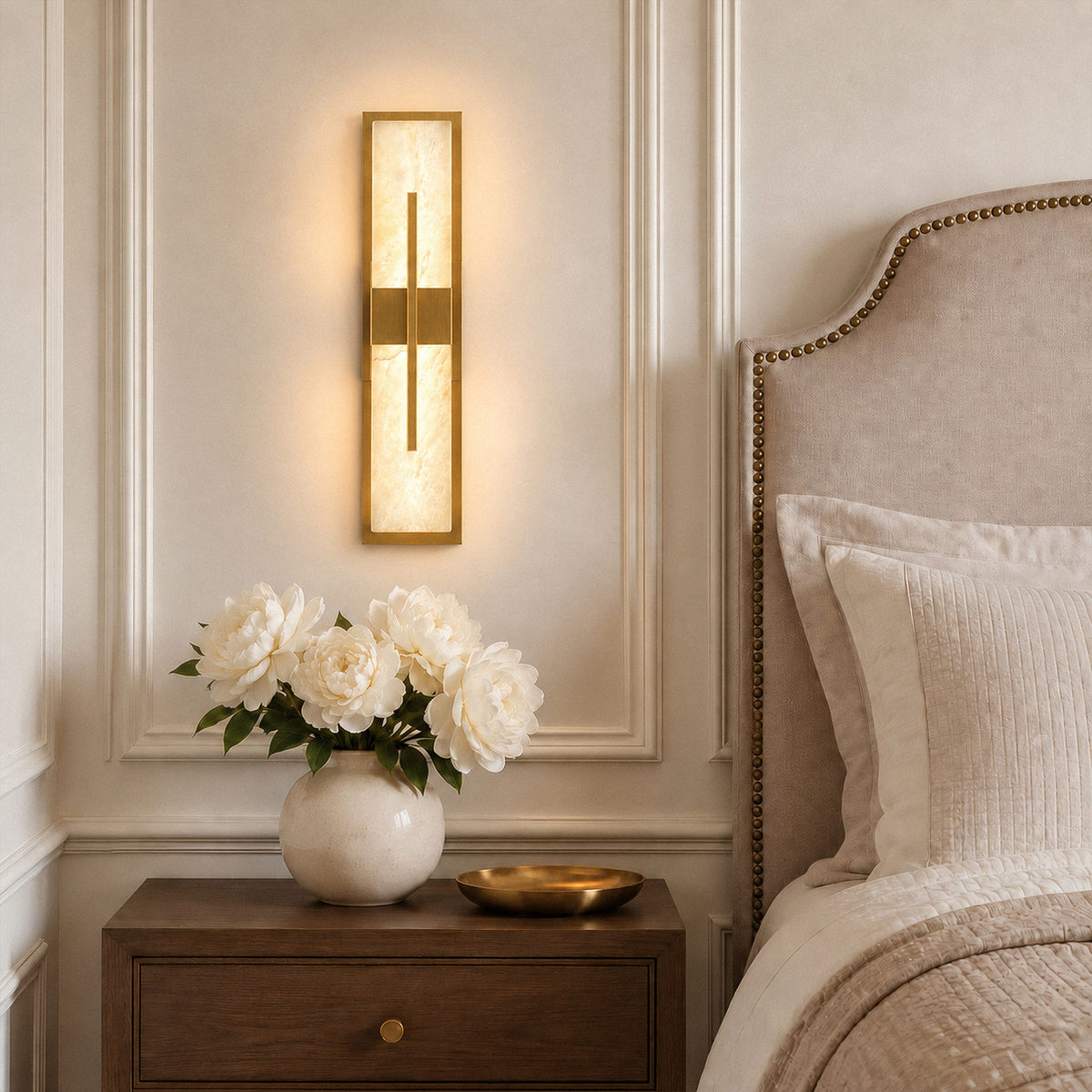 Illuminated rectangular Spanish natural alabaster wall sconce with brushed brass frame mounted above a bedside table in an elegant bedroom setting