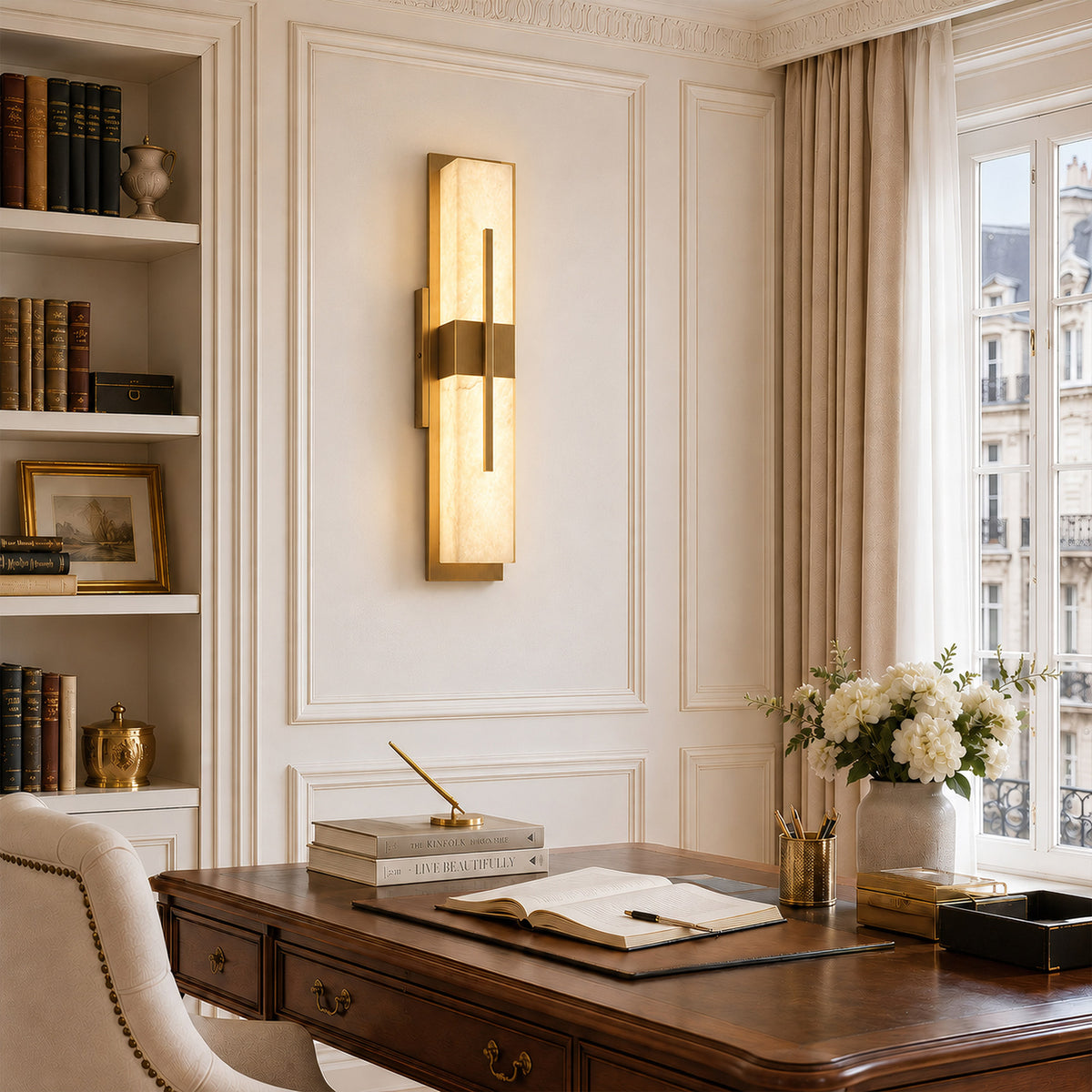 Glowing rectangular Spanish natural alabaster wall sconce installed on cream wall beside dark wood desk and bookshelves in classical study