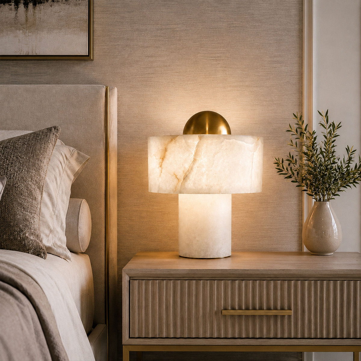 Front view of illuminated Spanish alabaster table lamp on fluted wooden nightstand beside bed
