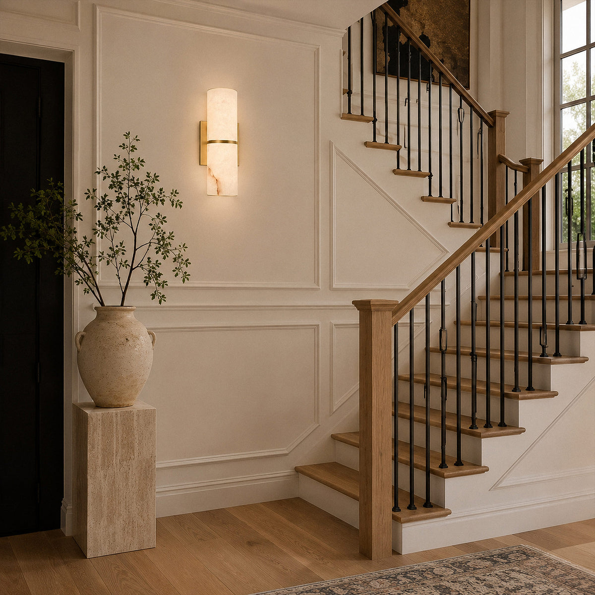 Illuminated Spanish alabaster wall light mounted near modern wooden staircase and entryway vase display