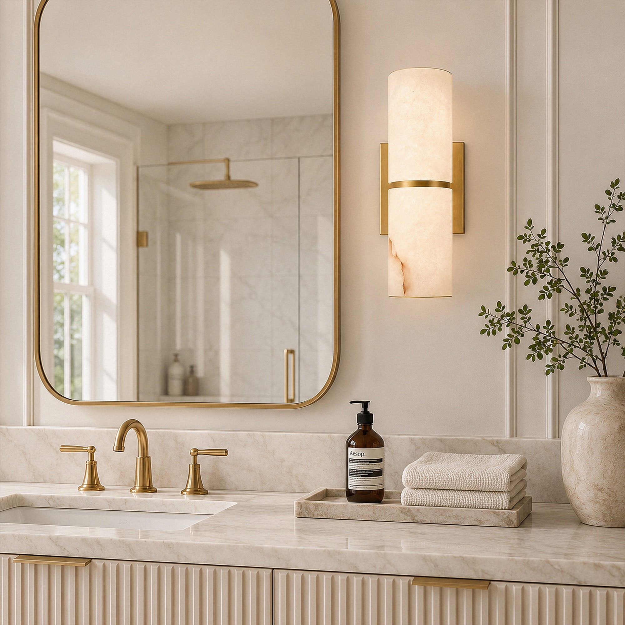 Spanish alabaster wall sconce mounted beside brass vanity mirror on bathroom wall