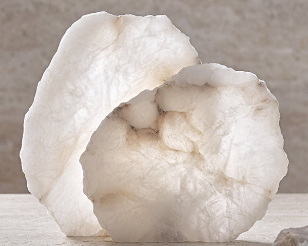 Layered round Spanish alabaster slabs illuminated by ambient light highlighting unique soft glow white marbling and delicate brown streaks.