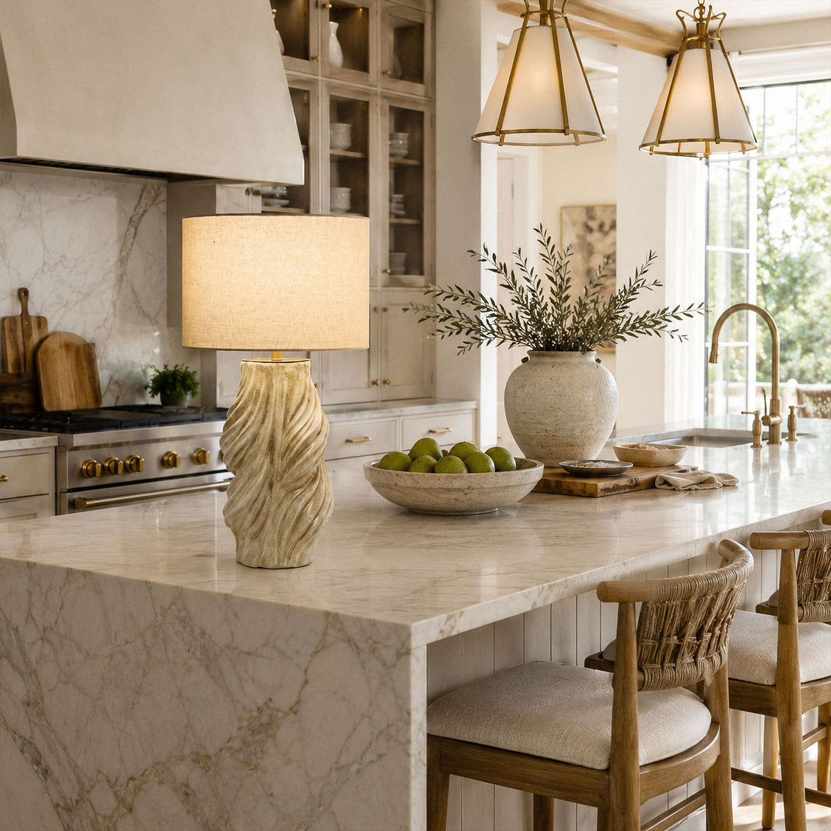 Illuminated artisan ceramic table lamp placed on marble kitchen island counter with bar stools