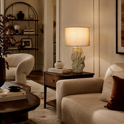 Handmade ceramic table lamp radiating warm light on side table near sofa in stylish living room