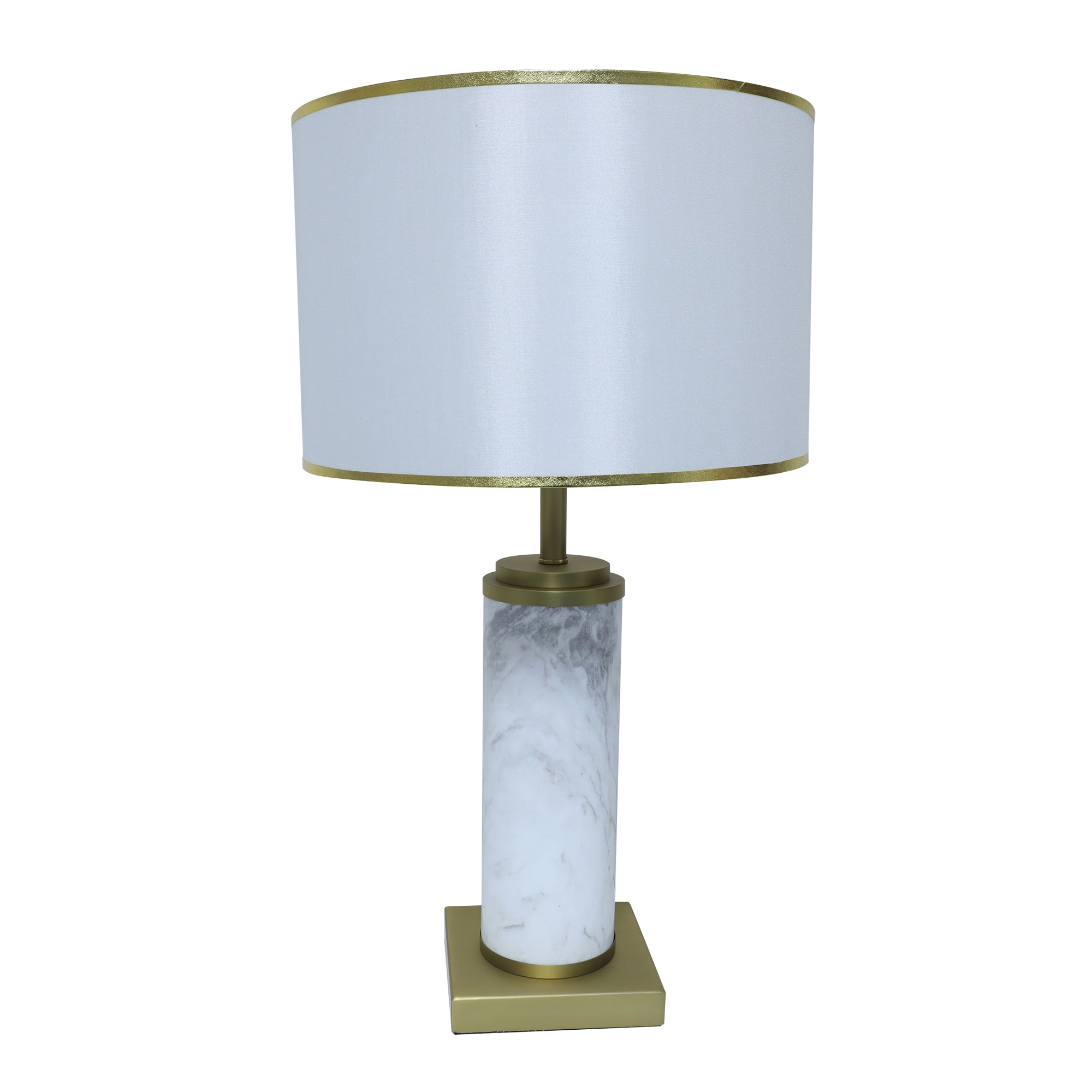 White marble cylinder table lamp with brass metal base and brass trim fabric shade turned off on white background