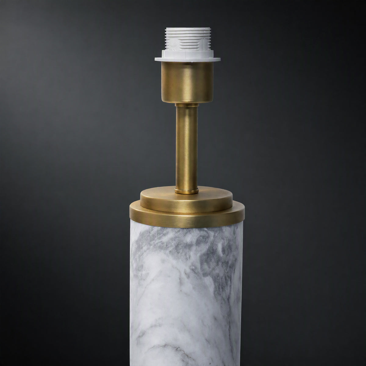 Close up detail of white marble cylinder body connected to brushed brass metal neck socket