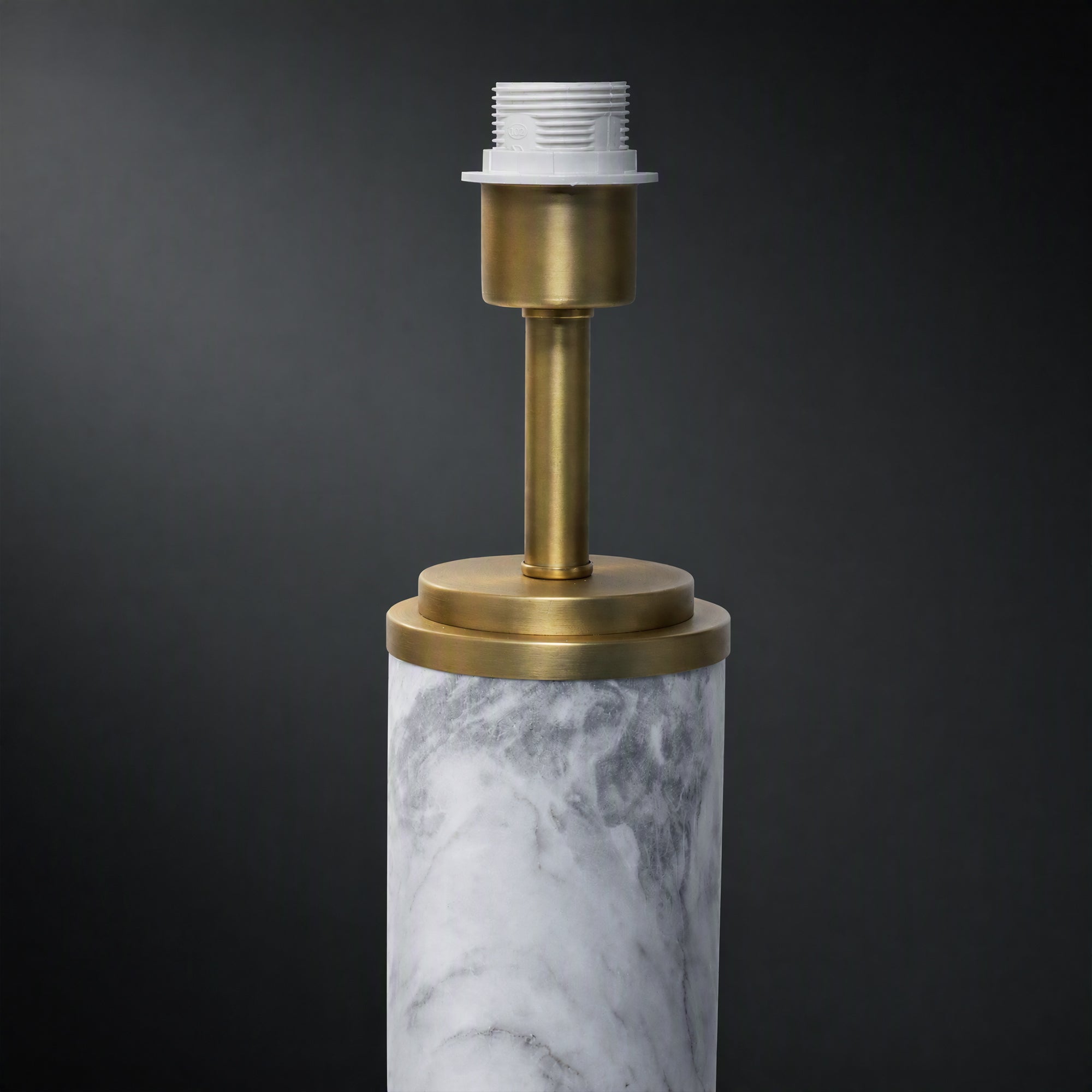 Close up detail of white marble cylinder body connected to brushed brass metal neck socket