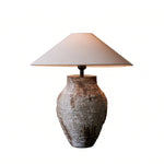 Artistic white rustic ceramic table lamp with light turned on isolated on a clean background.