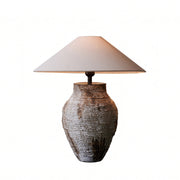 Artistic white rustic ceramic table lamp with light turned on isolated on a clean background.